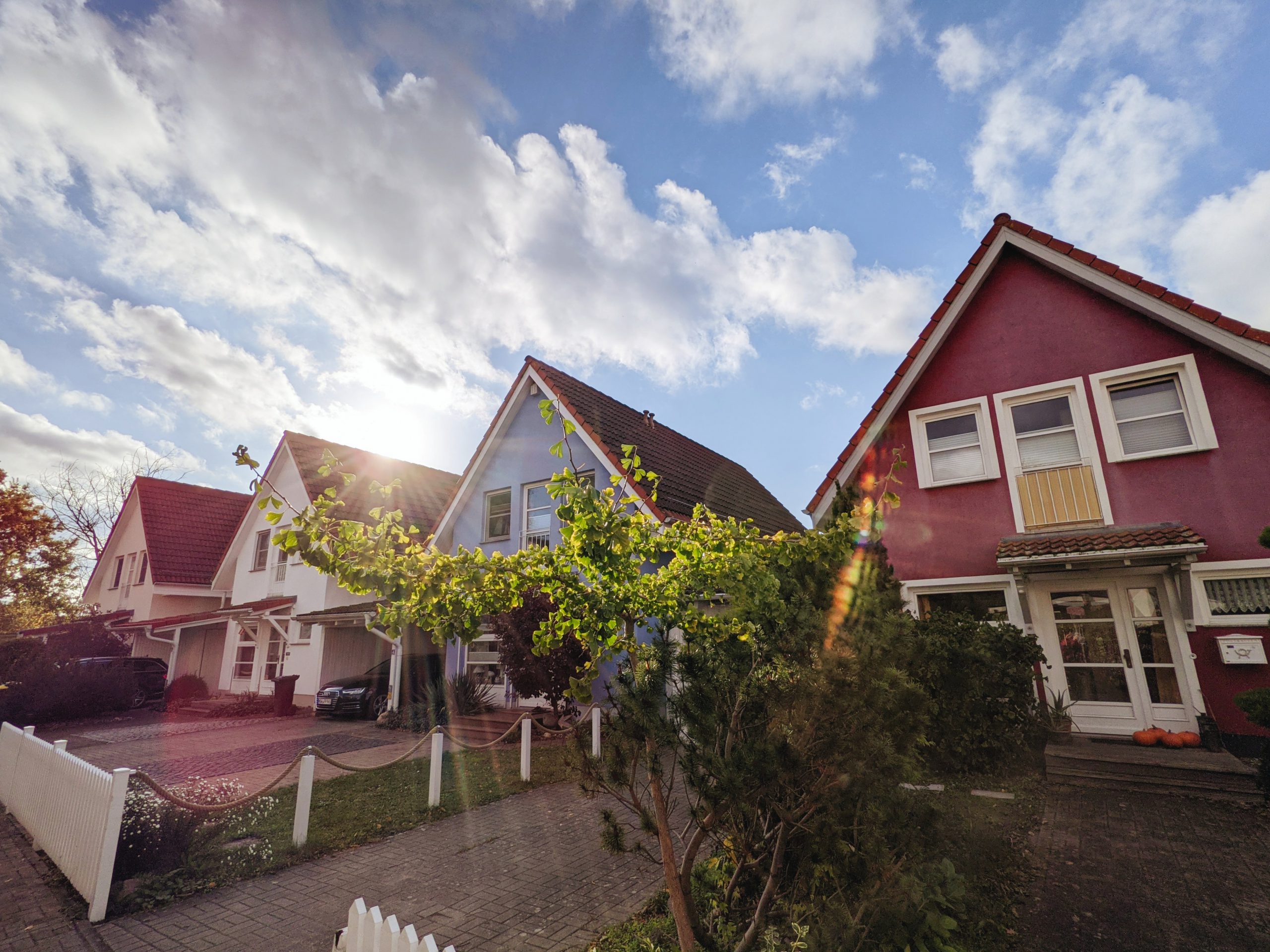 Imagem de casas vizinhas com luz do sol e nuvens.